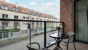 A balcony with a table and chairs, a view of a street with buildings, and a sign for "Onikii Automatyki".