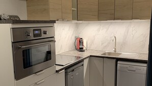 A modern kitchen with a built-in oven, dishwasher, and a coffee maker.