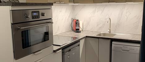 A modern kitchen with a built-in oven, dishwasher, and a coffee maker.