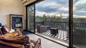 A room with a large sliding glass door leading to an outdoor deck with wicker furniture and a checkered floor. - Experience luxury at Sedona Red Mountain Retreat, a spacious 3-bedroom house with stunning views. (Sedona)