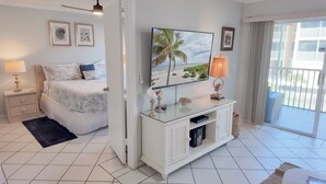 A bedroom with a bed, a nightstand, a TV, a console table, and a balcony with a view.