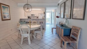 A modern kitchen with white cabinets, a dining table with white chairs, and a blue cabinet with decorative items.