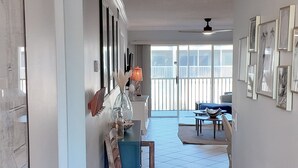 A spacious living area with a dining table and chairs, a blue sofa, and a large window with a view of the outside.