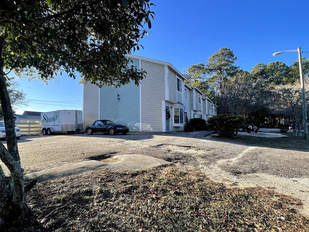 A residential area with a two-story house, a parked car, and a landscaping trailer.