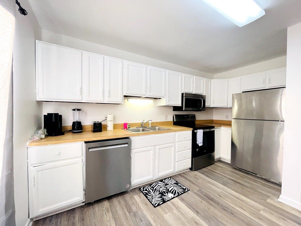 A modern kitchen with white cabinets, a stainless steel refrigerator, a dishwasher, and a microwave.