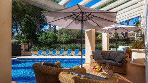 Ein Poolbereich mit Korbmöbeln, einem Tisch mit Getränken und einem Pool.