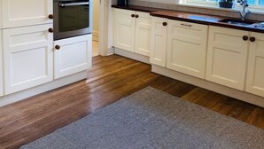 A kitchen with white cabinetry, a double oven, a window with a view, and a wooden floor. - Bright Modern Welcoming Home Easy Stroll Along Pathway Into Kenmare Town (Kenmare)