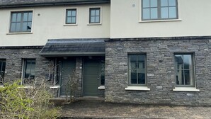 A two-story house with a stone facade, a dark roof, and a chimney. - Bright Modern Welcoming Home Easy Stroll Along Pathway Into Kenmare Town (Kenmare)