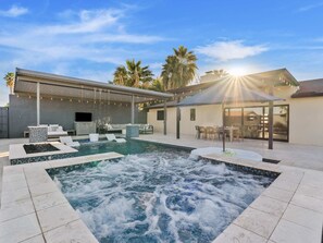 A modern outdoor pool area with a hot tub, seating, and a covered patio. - Luxury Old Town Scottsdale Home with Pool and Spa (Scottsdale)