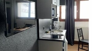 Eine kompakte Küche mit Einbau-Mikrowelle, Spüle und einem Fenster mit Vorhängen.