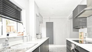 Une cuisine moderne avec des meubles de couleur sombre, des plans de travail blancs et un îlot central.