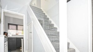 Un escalier muni d’une rampe et de marches recouvertes de moquette, menant à une porte.