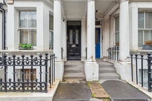 Classic townhouse with a central entrance, flanked by two columns, and a black iron gate.