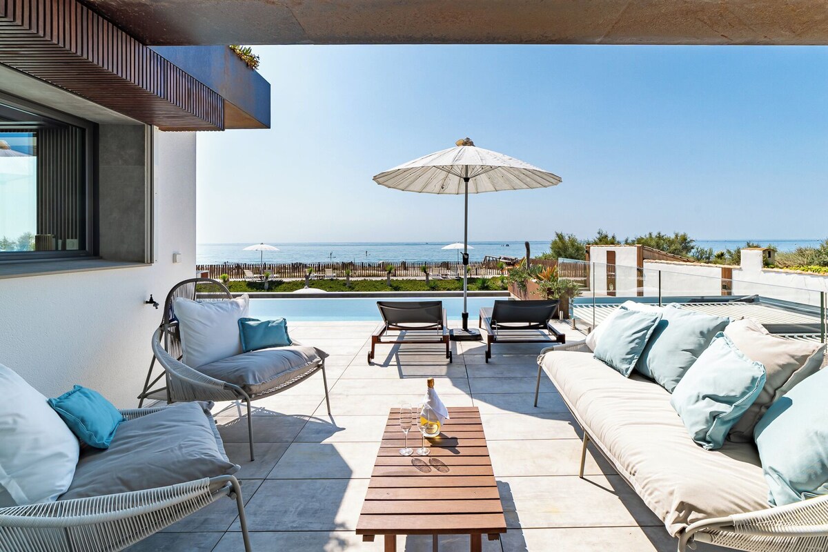 A rooftop terrace with outdoor seating, a pool, and a view of the sea.