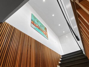Ein modernes Interieur mit einer Wand aus Holzlatten, einer Treppe und einem farbenfrohen Gemälde.