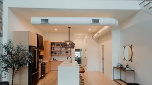 A modern kitchen with a central island, wooden cabinets, and a hanging light fixture.