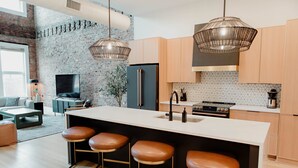A modern kitchen with a large island, bar stools, and pendant lighting.