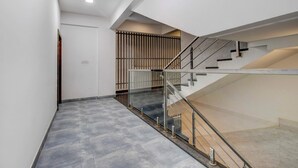 Un escalier moderne avec des rampes en verre et une main courante en métal, menant à l’étage supérieur.