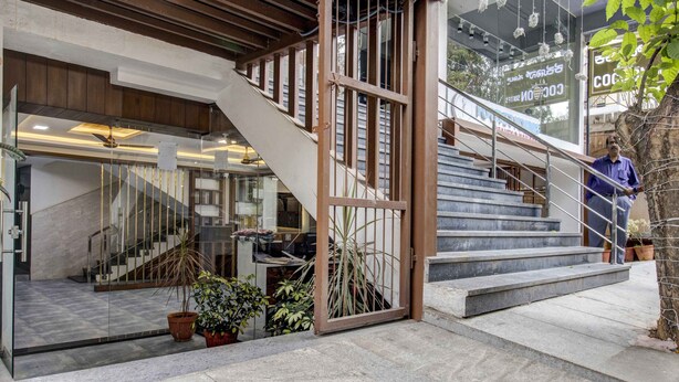 Une entrée moderne avec un escalier, des portes vitrées et des plantes en pot.