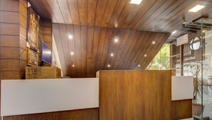Un espace d’accueil avec un lambris en bois, un téléviseur et une porte en verre portant une inscription.