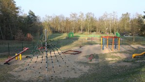 A playground with various play structures including a climbing net, seesaw, and swings. - New! Haus Seebrise - at Useriner See - Müritz National Park (Userin)