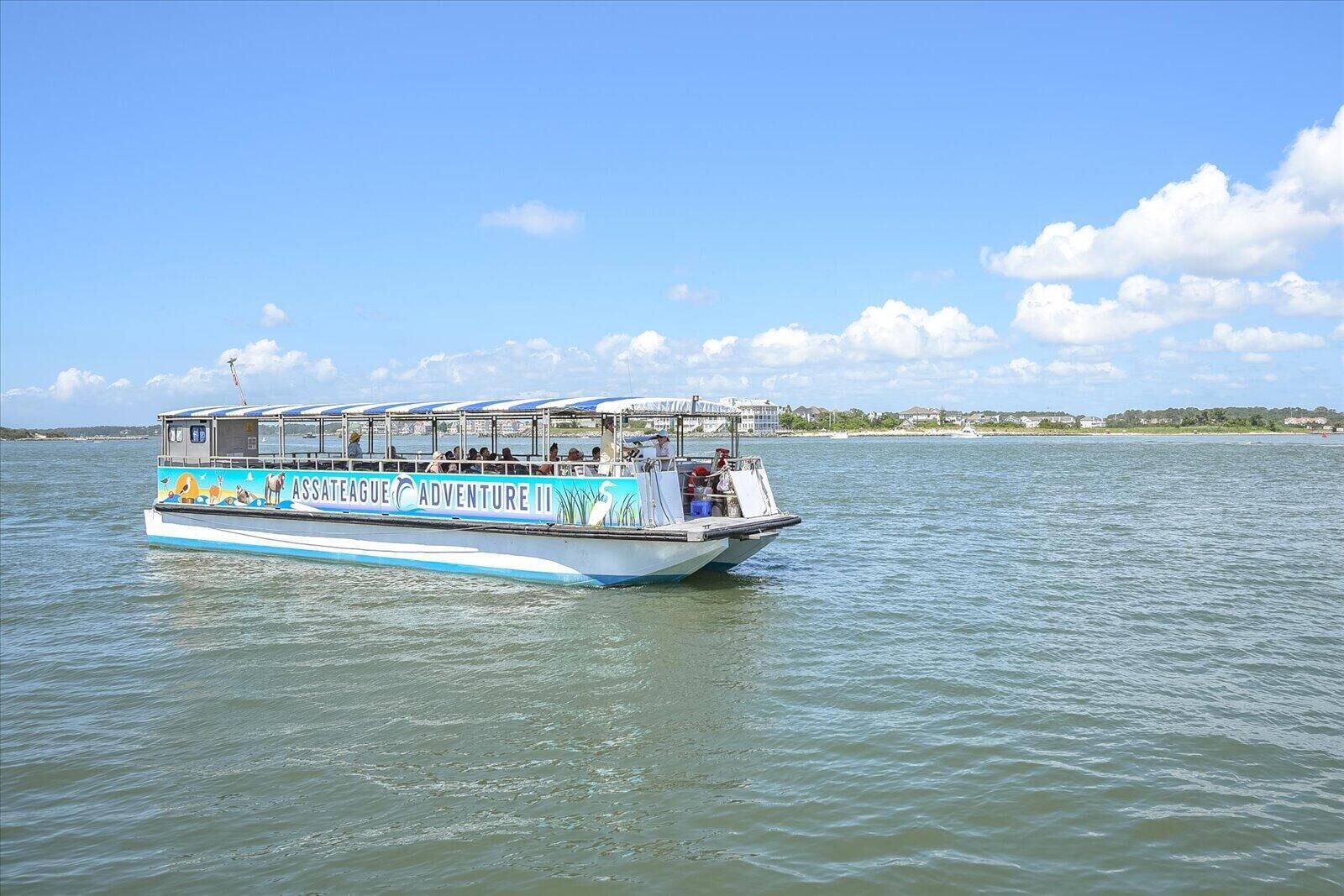 A boat with "ASSATAGE ADVENTURE II" written on its side, floating on calm water.