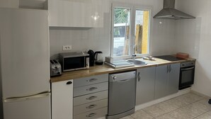 Una cocina moderna con armarios blancos, microondas integrado, cafetera y lavavajillas.