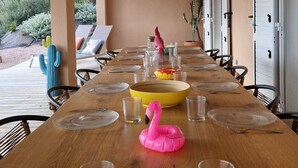 Una larga mesa de comedor con cristalería transparente, una decoración de flamenco rosa y protectores de mesa tejidos.