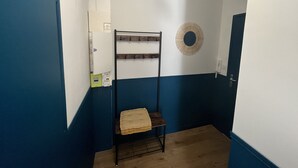 A narrow hallway with blue walls, a bunk bed with a wooden seat, a wall-mounted light fixture, and a power outlet. - Studio LA Fregate - Proche Centre Lorient (Lorient)
