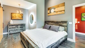 Ein modernes Schlafzimmer mit einem Holzkopfteil, einem großen Bett, einer Kommode und einem wandmontierten Spiegel.