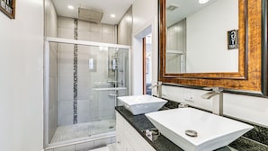 Ein modernes Badezimmer mit einer Duschkabine, zwei Waschbecken und einem großen Spiegel.