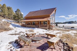 A lodge with a wooden exterior, a covered patio with benches, and a view of a snowy landscape. - Cozy Duck Creek Village Cabin w/ Hot Tub & Views! (Duck Creek Village)