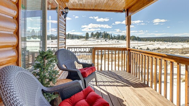 A wooden deck with two wicker chairs and a small Christmas tree. - Cozy Duck Creek Village Cabin w/ Hot Tub & Views! (Duck Creek Village)