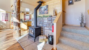 A cozy interior with a stone fireplace, wooden beams, and a kitchen area. - Cozy Duck Creek Village Cabin w/ Hot Tub & Views! (Duck Creek Village)