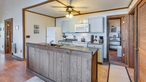 A kitchen with wooden cabinetry, a central island, a ceiling fan, and a microwave. - Smoky Mountain Cabin w/ Fire Pit & Stunning Views! (Andrews)