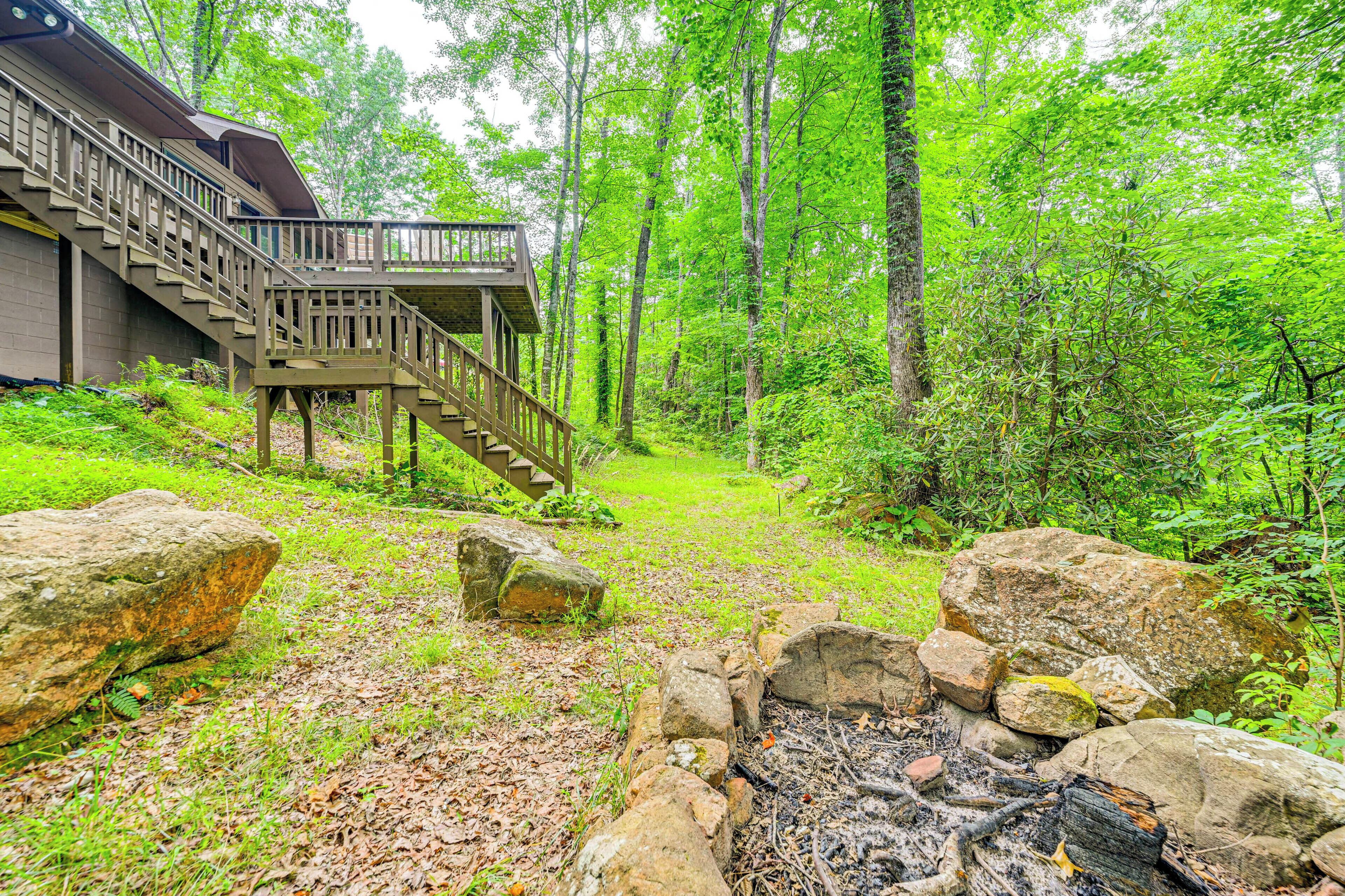 A cabin with a wooden staircase leading to a deck, surrounded by a forest.