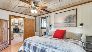 A bedroom with a bed, a ceiling fan, a fireplace, and a window with curtains. - Smoky Mountain Cabin w/ Fire Pit & Stunning Views! (Andrews)