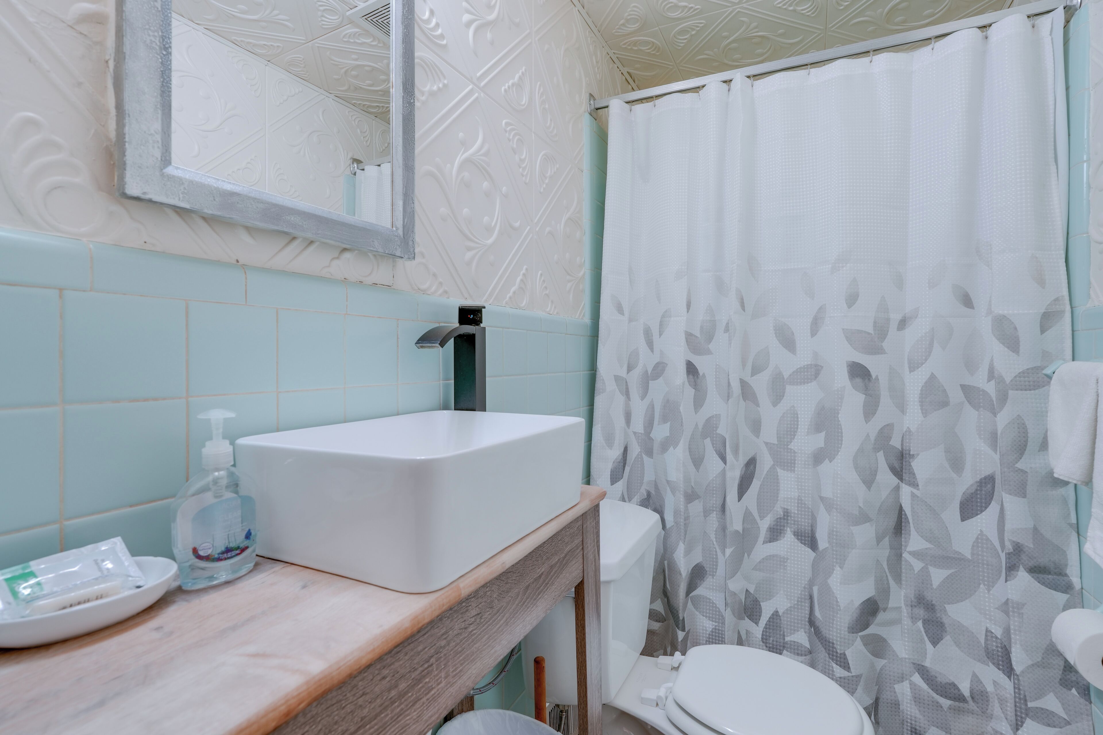 A bathroom with a white sink, a mirror, a toilet, and a shower curtain.