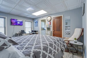 Un dormitorio con cama, escritorio, silla, televisión y puerta.