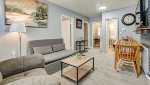 A living room with a grey sofa, a wooden coffee table, a lamp, a painting, and a chair. - Kalamazoo Vacation Rental Near Golf & Parks! (Kalamazoo)