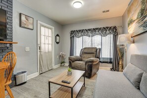 A living room with a grey sofa, a brown recliner, a wooden coffee table, and a TV mounted on a brick wall. - Kalamazoo Vacation Rental Near Golf & Parks! (Kalamazoo)