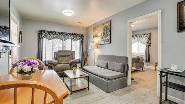 A living room with a sofa, armchair, dining table, and a painting on the wall. - Kalamazoo Vacation Rental Near Golf & Parks! (Kalamazoo)