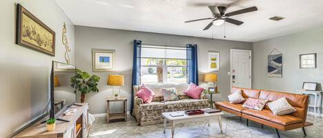 A living room with a sofa, a coffee table, a TV, and a ceiling fan.