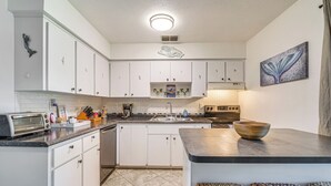 Eine Küche mit weißen Schränken, einer Arbeitsplatte aus Granit, einem Einbauofen und einem Spülbecken.