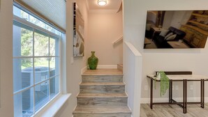 A staircase with a marble finish, a green vase on the landing, and a dining table with a hanging plant. - Modern Ocala Townhome w/ EV Charger Near WEC (Ocala)