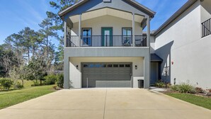 A two-story house with a garage, a balcony, and a well-maintained lawn. - Modern Ocala Townhome w/ EV Charger Near WEC (Ocala)