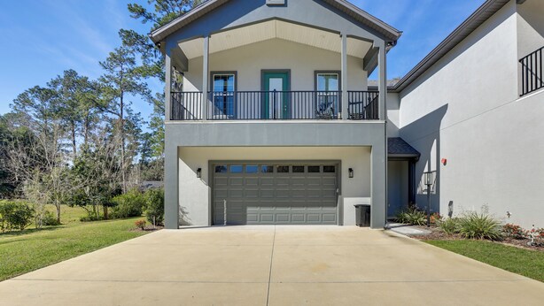 A two-story house with a garage, a balcony, and a well-maintained lawn. - Modern Ocala Townhome w/ EV Charger Near WEC (Ocala)