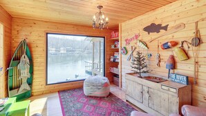 A cozy cabin interior with a large window, wooden walls, a chandelier, and various fishing memorabilia. - Please Note: No Boat Slip Available for Dock (Flippin)