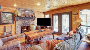 A cozy living room with a fireplace, wooden ceiling, and a large TV. - Please Note: No Boat Slip Available for Dock (Flippin)