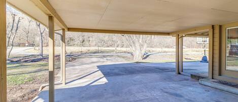 Un porche techado vacío con suelo de concreto y vigas de madera.